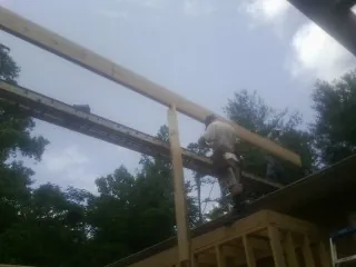 Carpenter setting a ridge beam over a new addition frame — Ice Dam Removal by Roofing Brothers in Avonmore