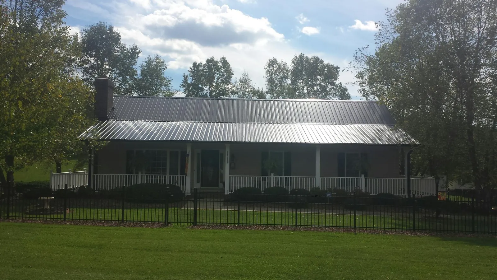 Gray metal roof on a brick ranch with a full width front porch — Gutter Guard Installation work by our crew in Avonmore