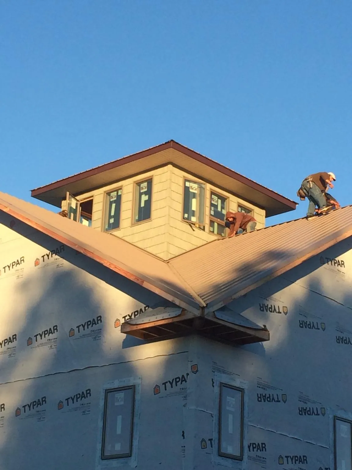 Roofers working around a rooftop cupola on a new metal roof at sunset — Roof Waterproofing in Avonmore by Roofing Brothers